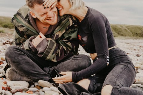 Ein Paar sitzt lachend und umarmend auf Steinen