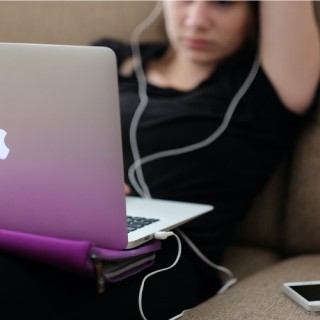 Eine Person mit Kopfhörern sitzt vor einem Laptop