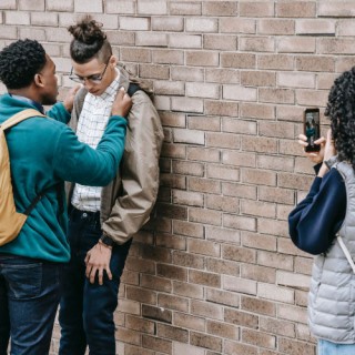 Frau filmt wie Junge gegen Wand gepresst wird.