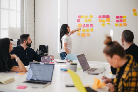 Gruppe arbeitet gemeinsam mit Laptops und Postits