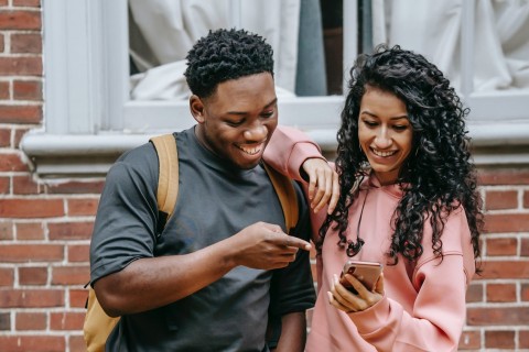 Ein Jugendlicher und eine Jugendliche schauen gemeinsam auf ein Smartphone