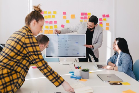 Workshopleiter erklärt etwas am Monitor, während das zu schulende Team zuschaut