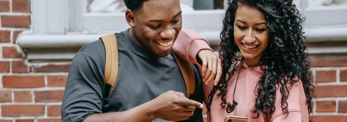 Ein Jugendlicher und eine Jugendliche schauen gemeinsam auf ein Smartphone
